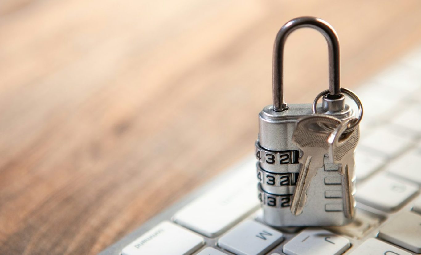 Photo of a person on a videocall on a laptop to a man. An open book is beside the laptop. We see this from over the shoulder of the caller.