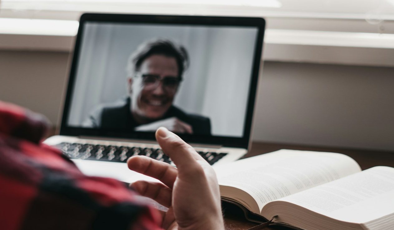 Photo of a silver padlock with two keys attached on top of the edge of a Mac laptop keyboard on a wood table, representing digital security.